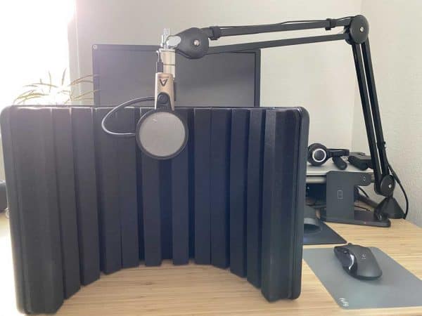 A microphone attached to the desk with a pop filter.
